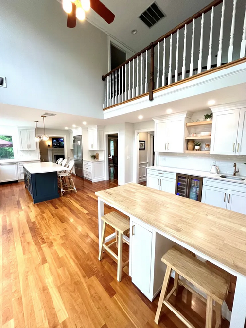 A kitchen with wooden floors and white cabinets.