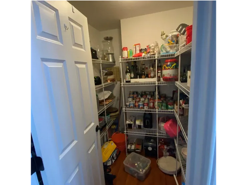 A pantry with many shelves of food and a door open.