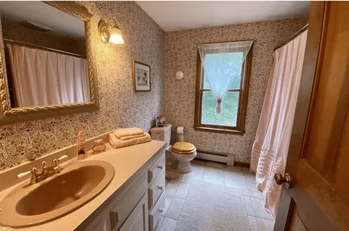 A bathroom with a sink, toilet and mirror.