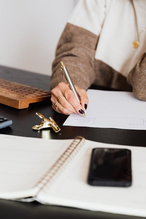 A person writing on paper with a pen.