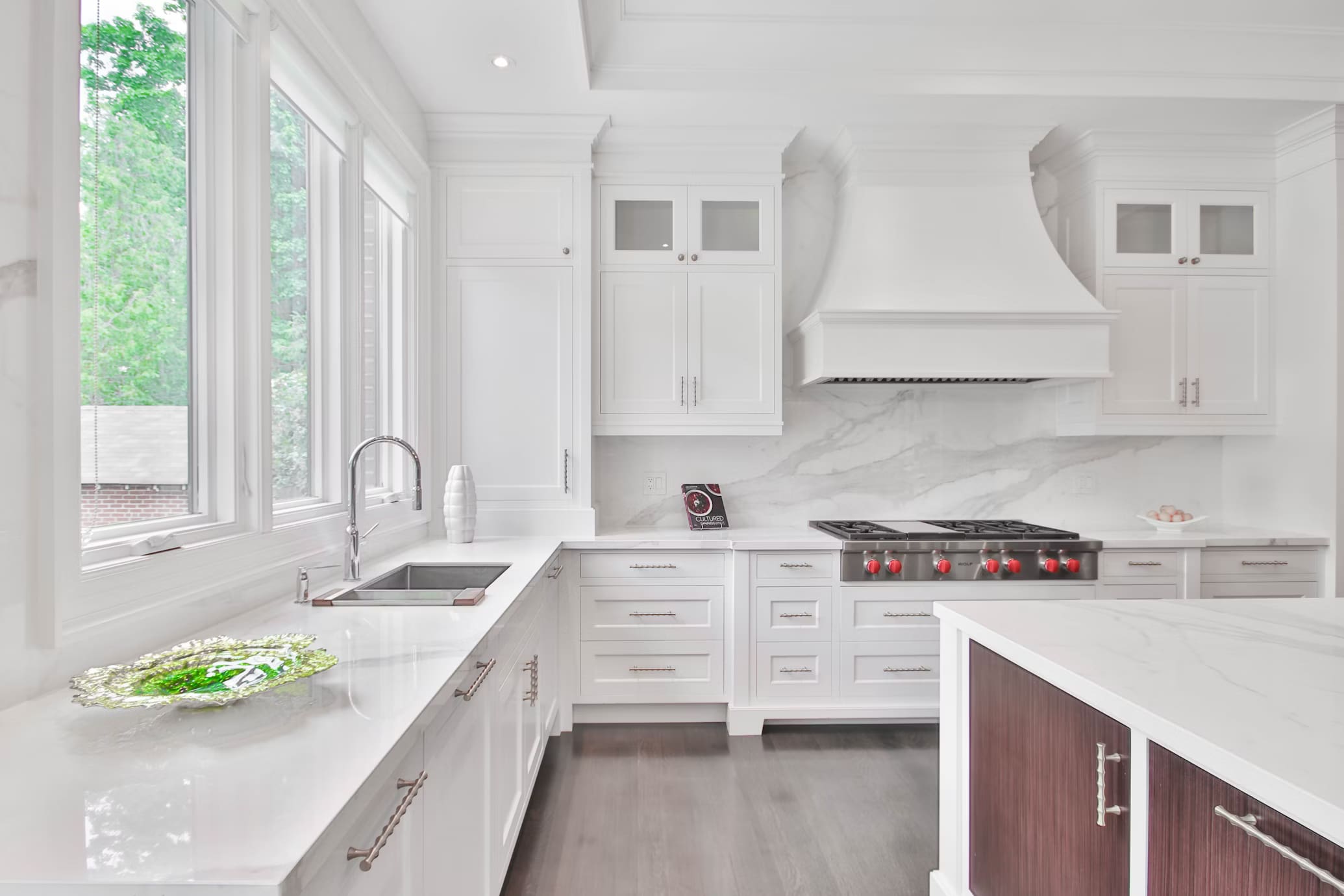 A kitchen with white cabinets and marble counters.