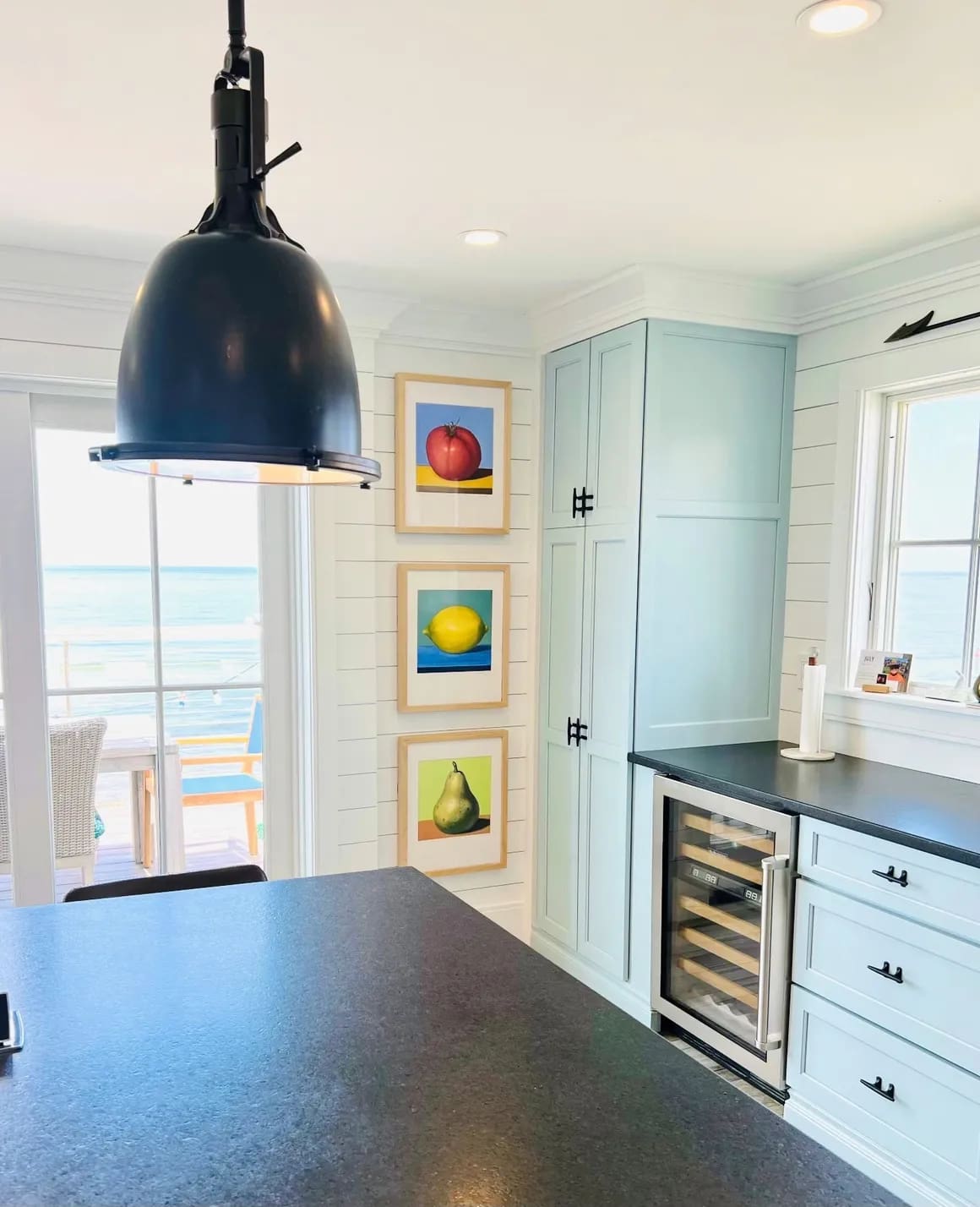 A kitchen with a view of the ocean and a black counter.