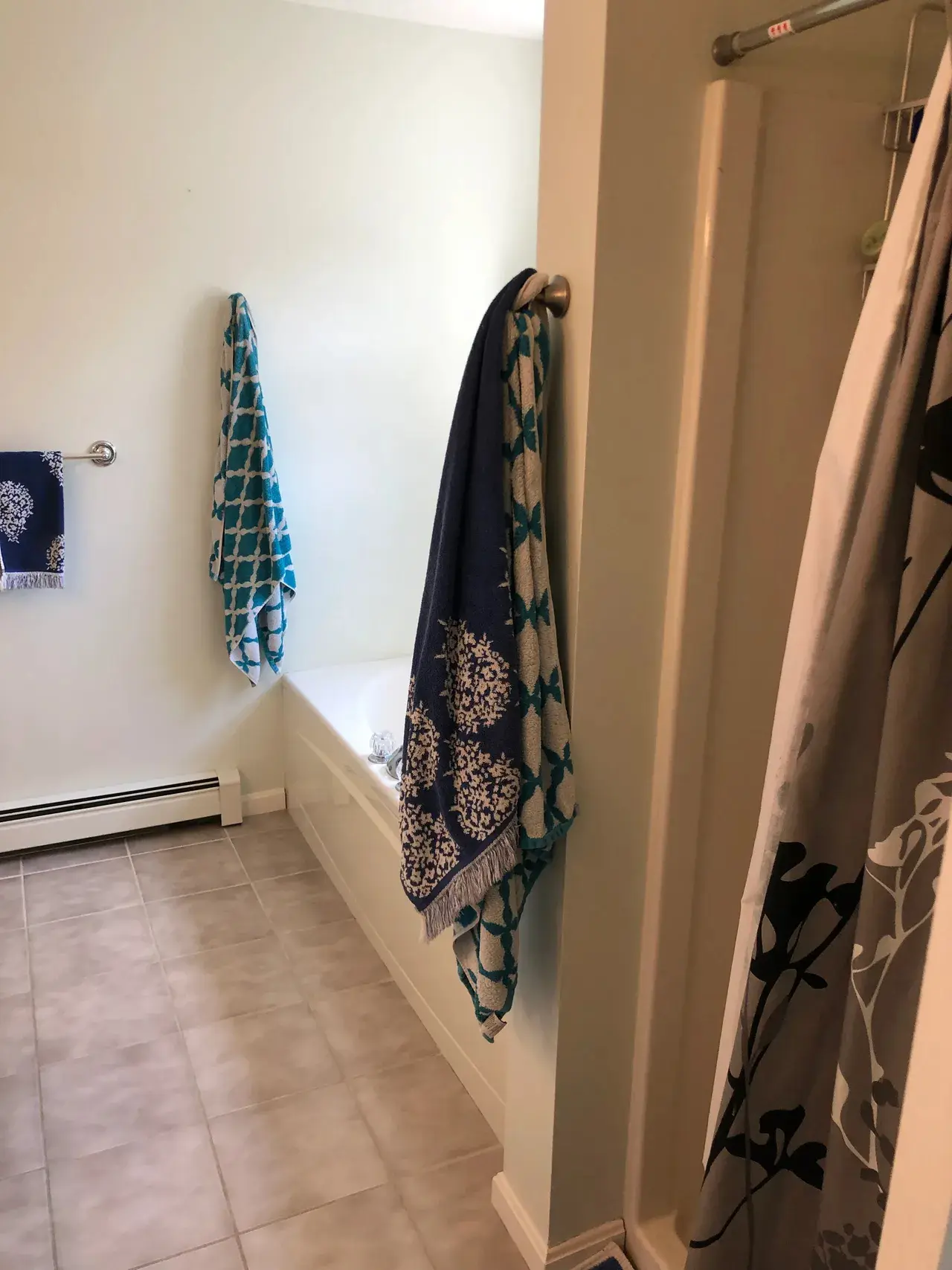 A bathroom with a tub and towels hanging on the wall.