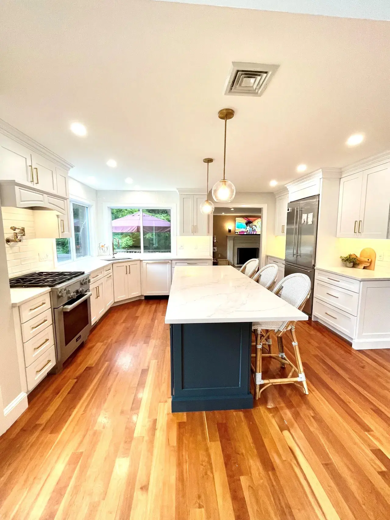 A kitchen with white cabinets and wood floors.