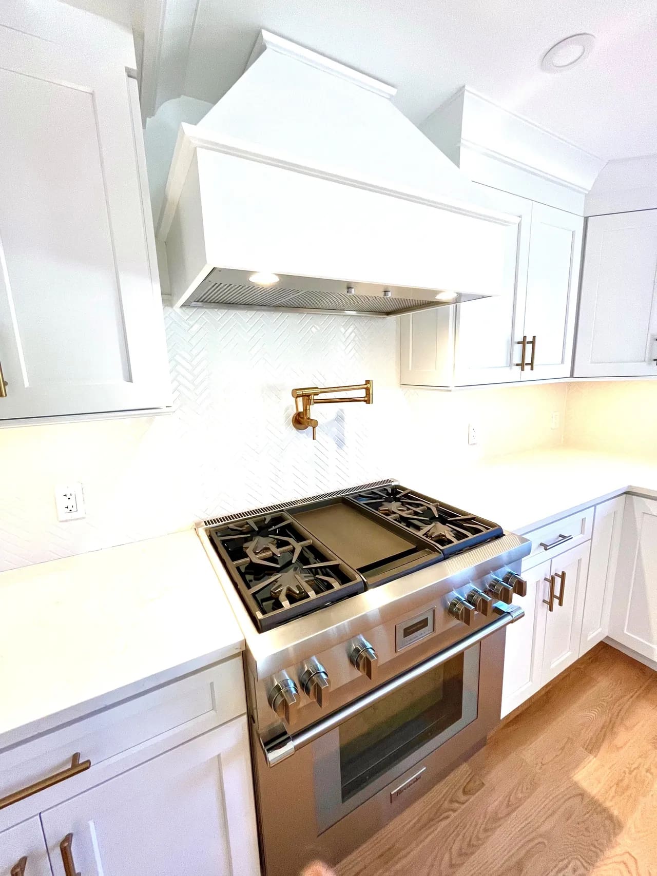 A kitchen with white cabinets and stainless steel stove.