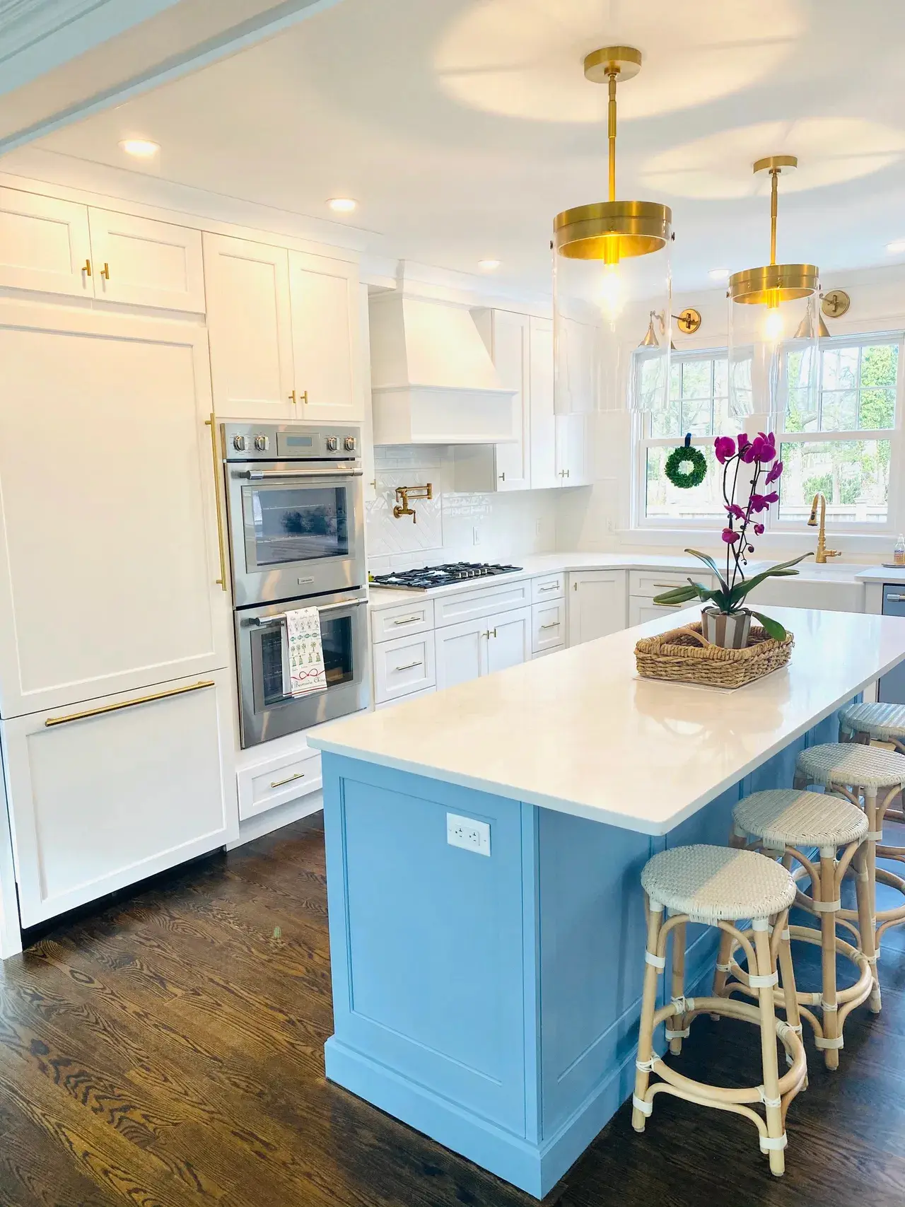 A kitchen with white cabinets and blue island.