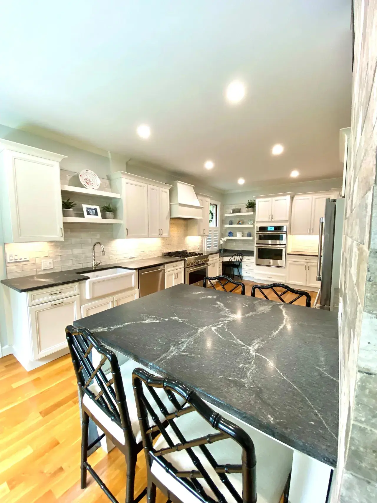 A kitchen with marble counter tops and white cabinets.