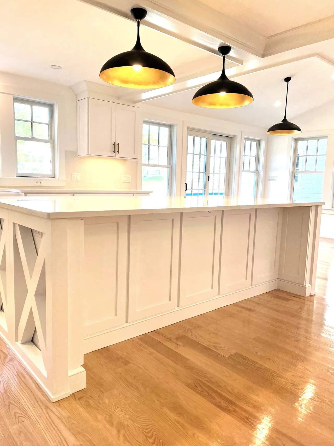 A kitchen with white cabinets and wooden floors.