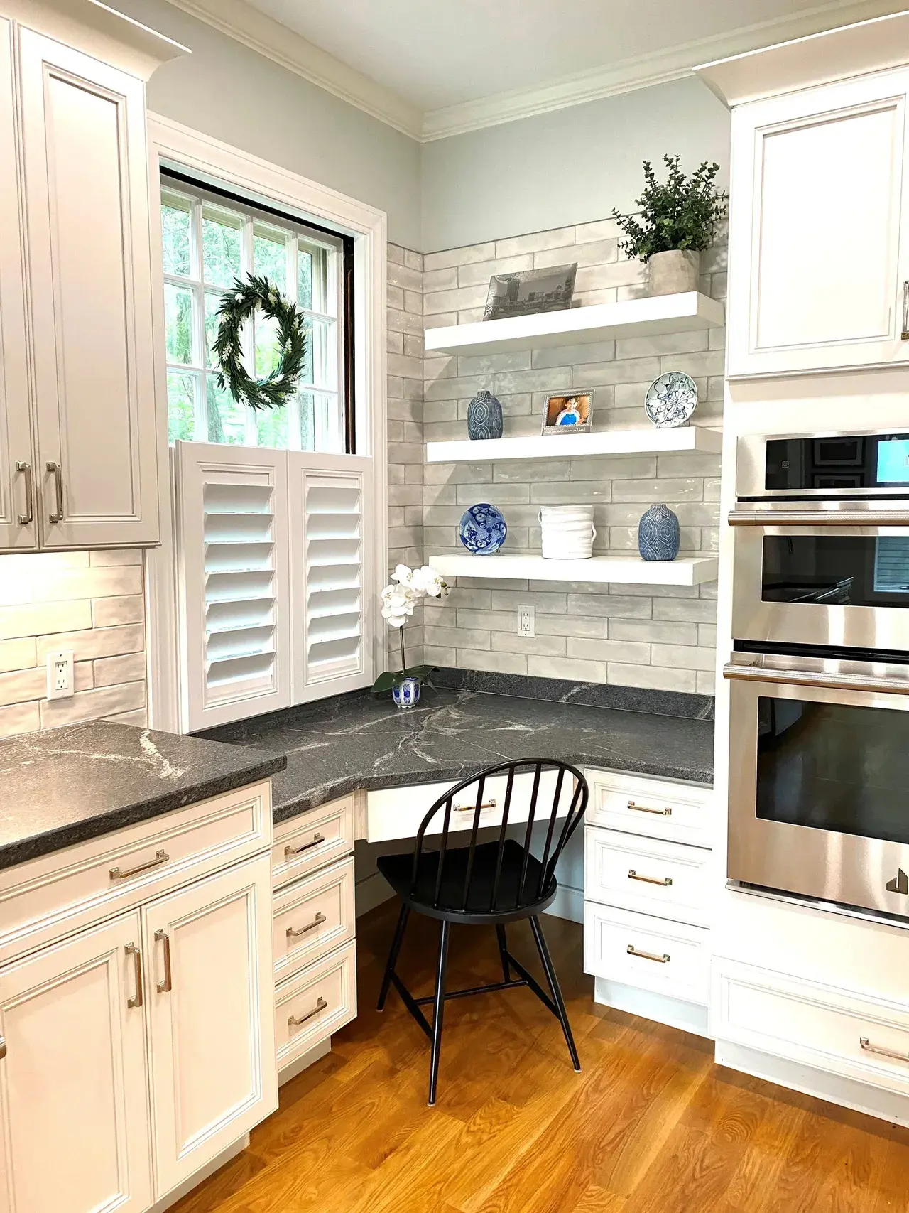 A kitchen with white cabinets and black counter tops.