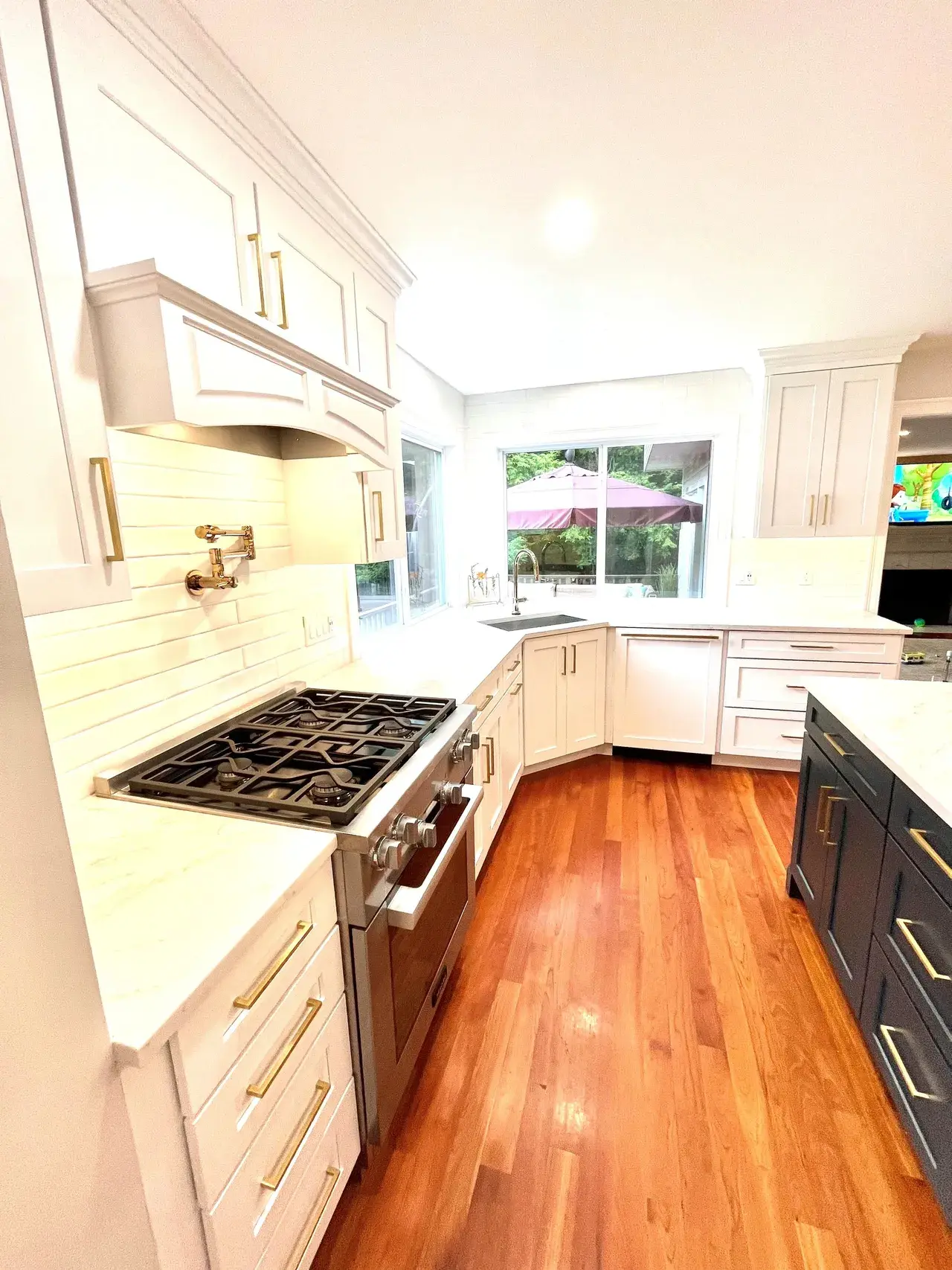 A kitchen with white cabinets and wood floors.