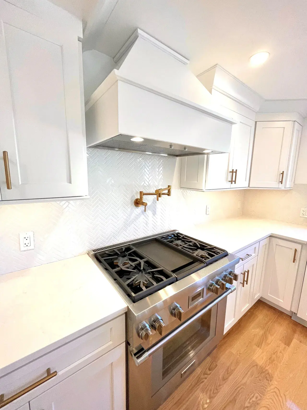 A kitchen with white cabinets and stainless steel stove.