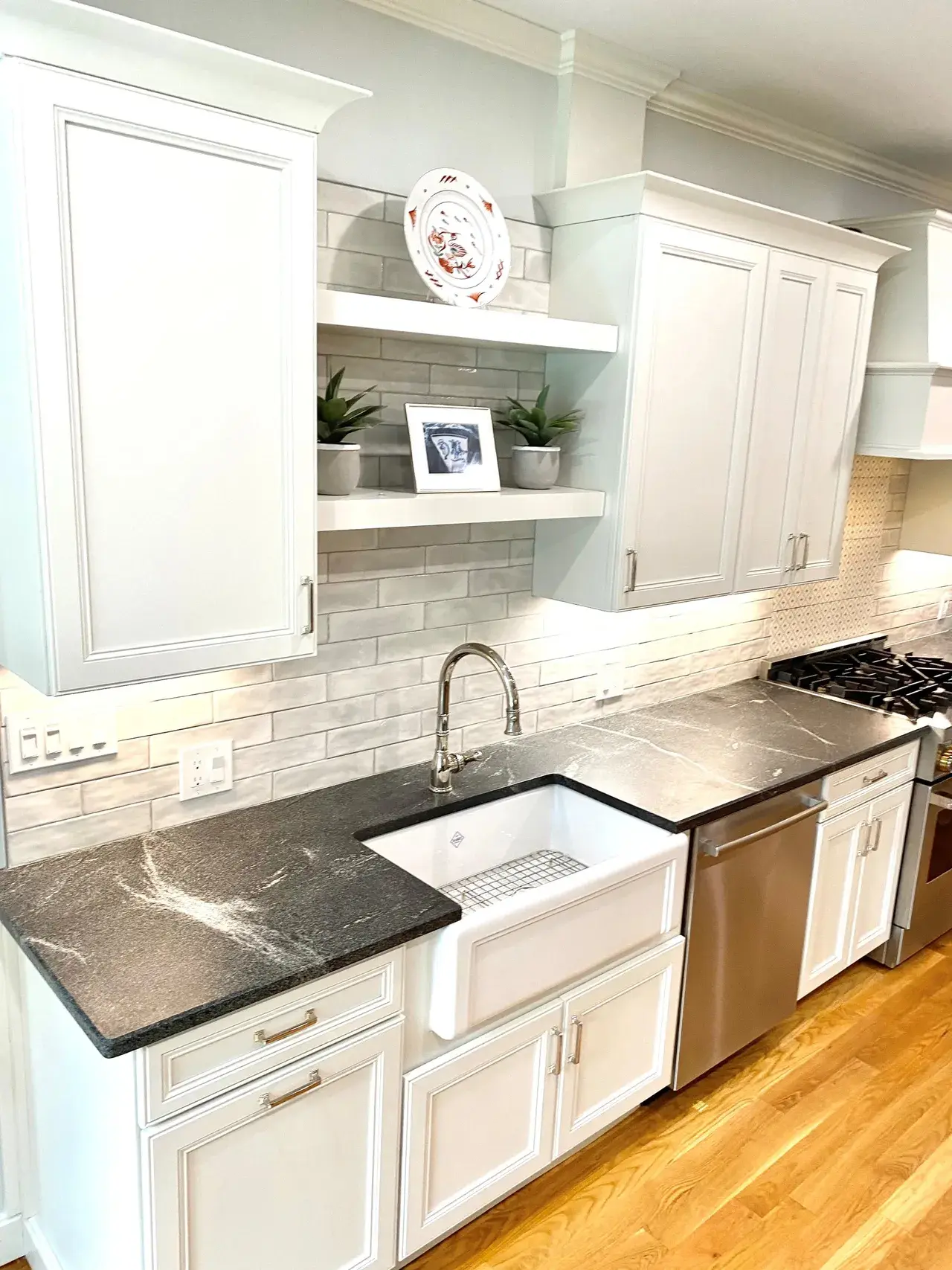 A kitchen with white cabinets and black counter tops.