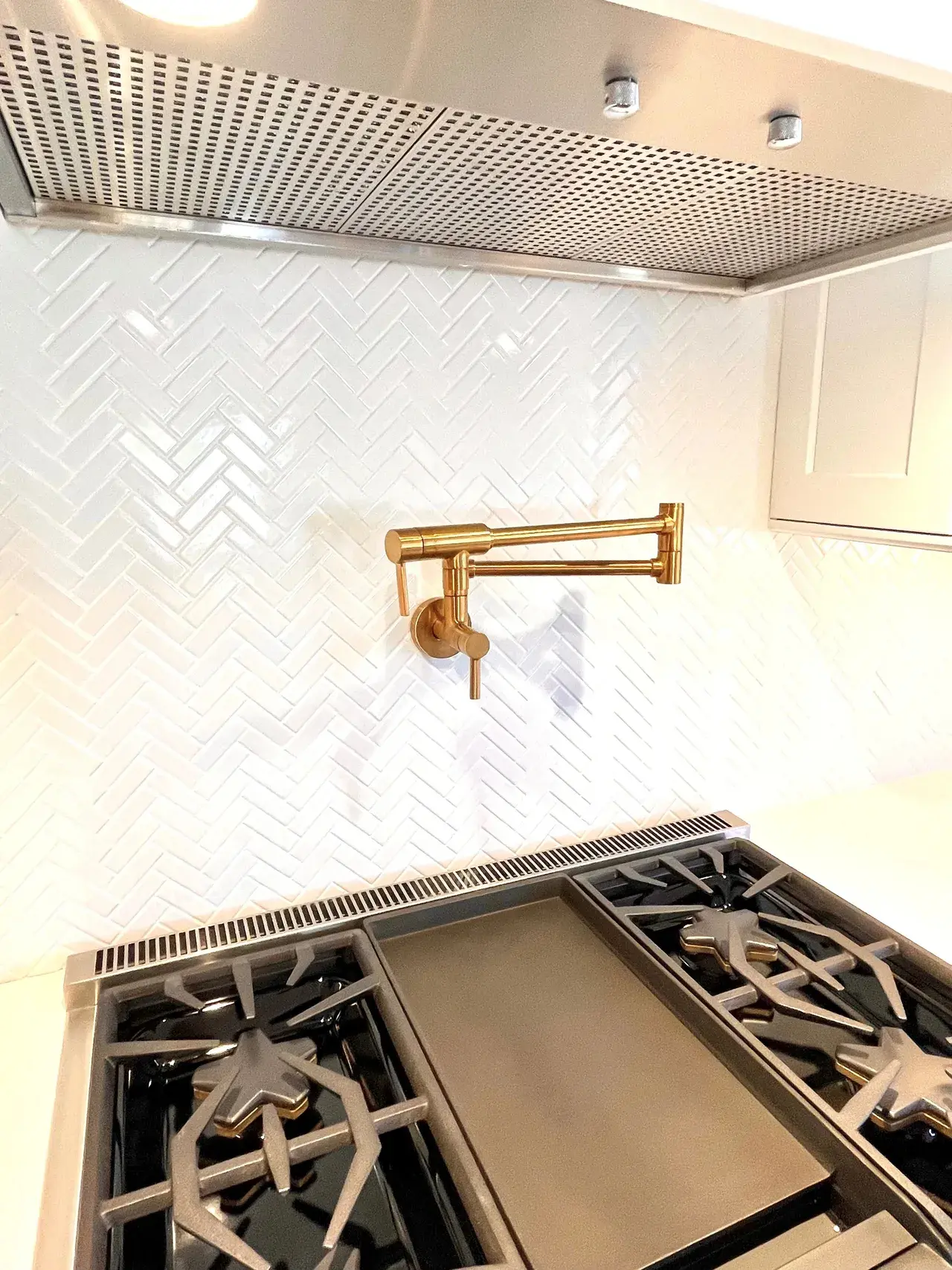 A kitchen with white walls and gold fixtures.