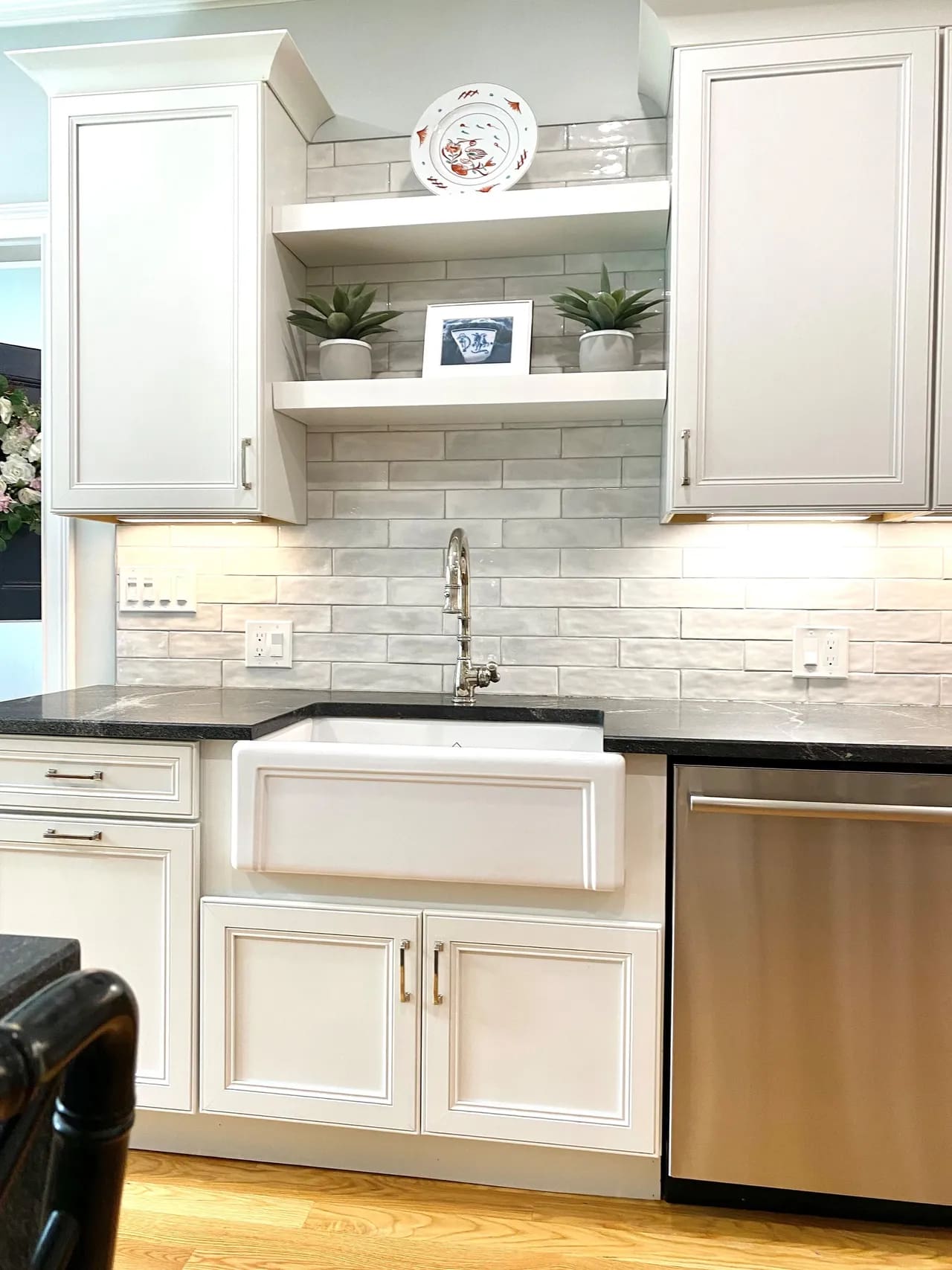 A kitchen with white cabinets and black counter tops.