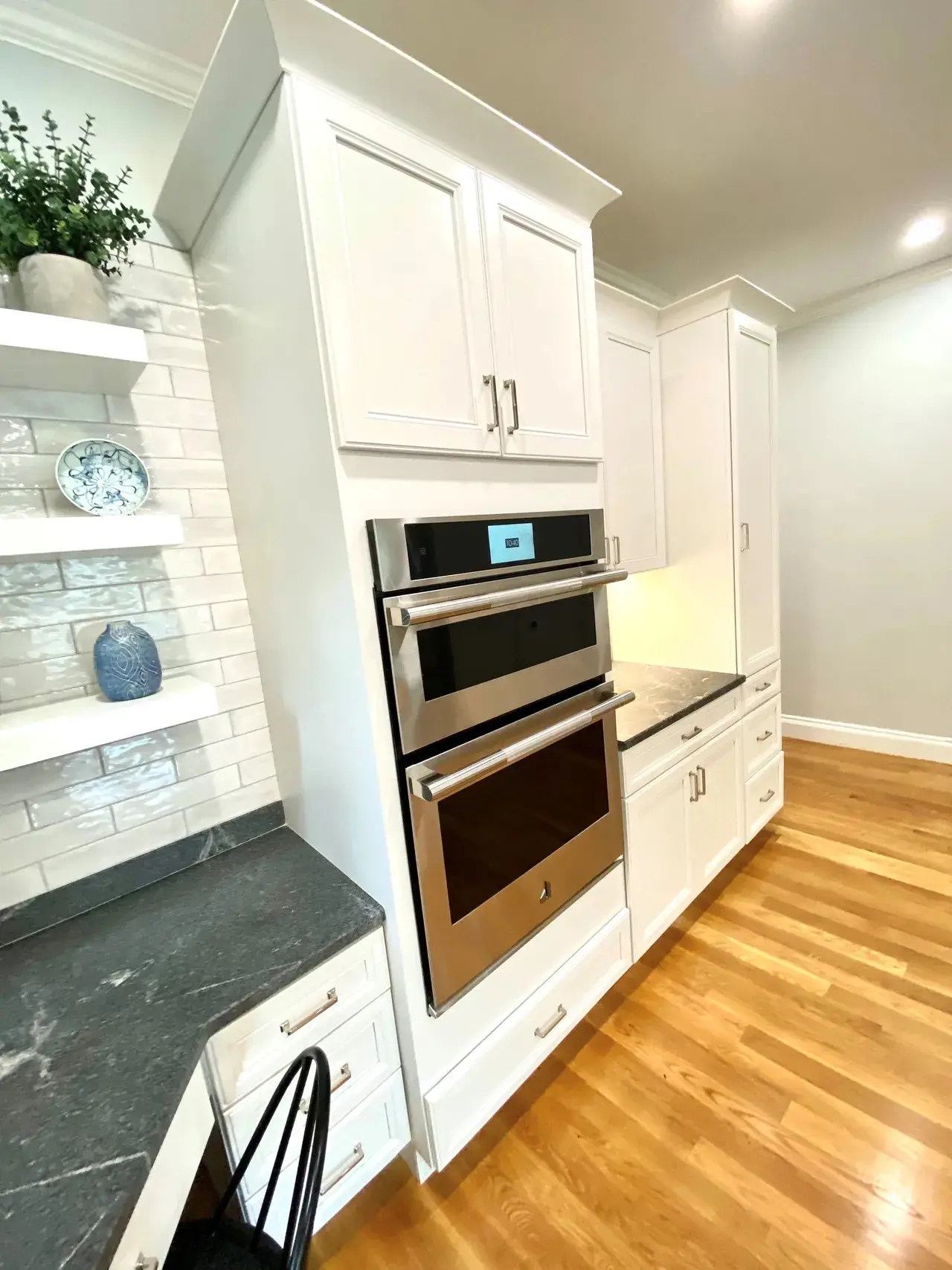 A kitchen with white cabinets and wood floors.