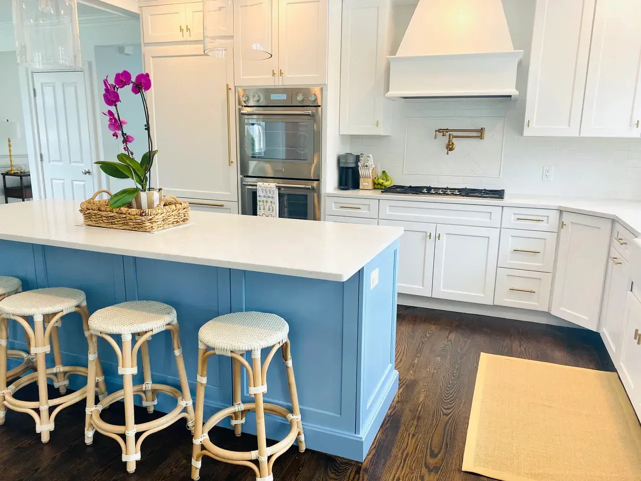 A kitchen with white cabinets and blue island.