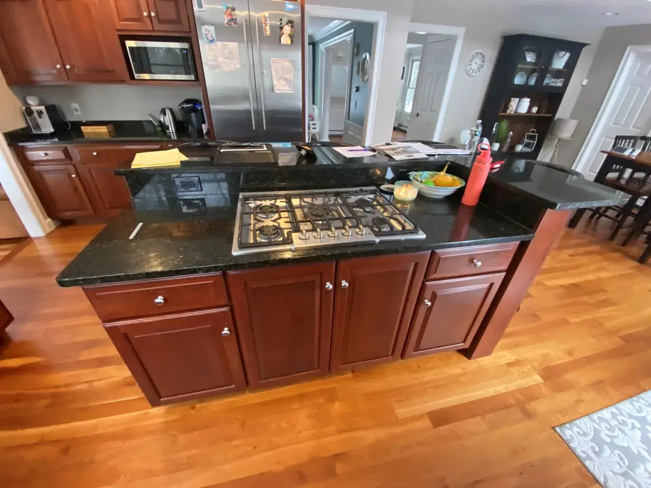 A kitchen with wood floors and black counter tops.