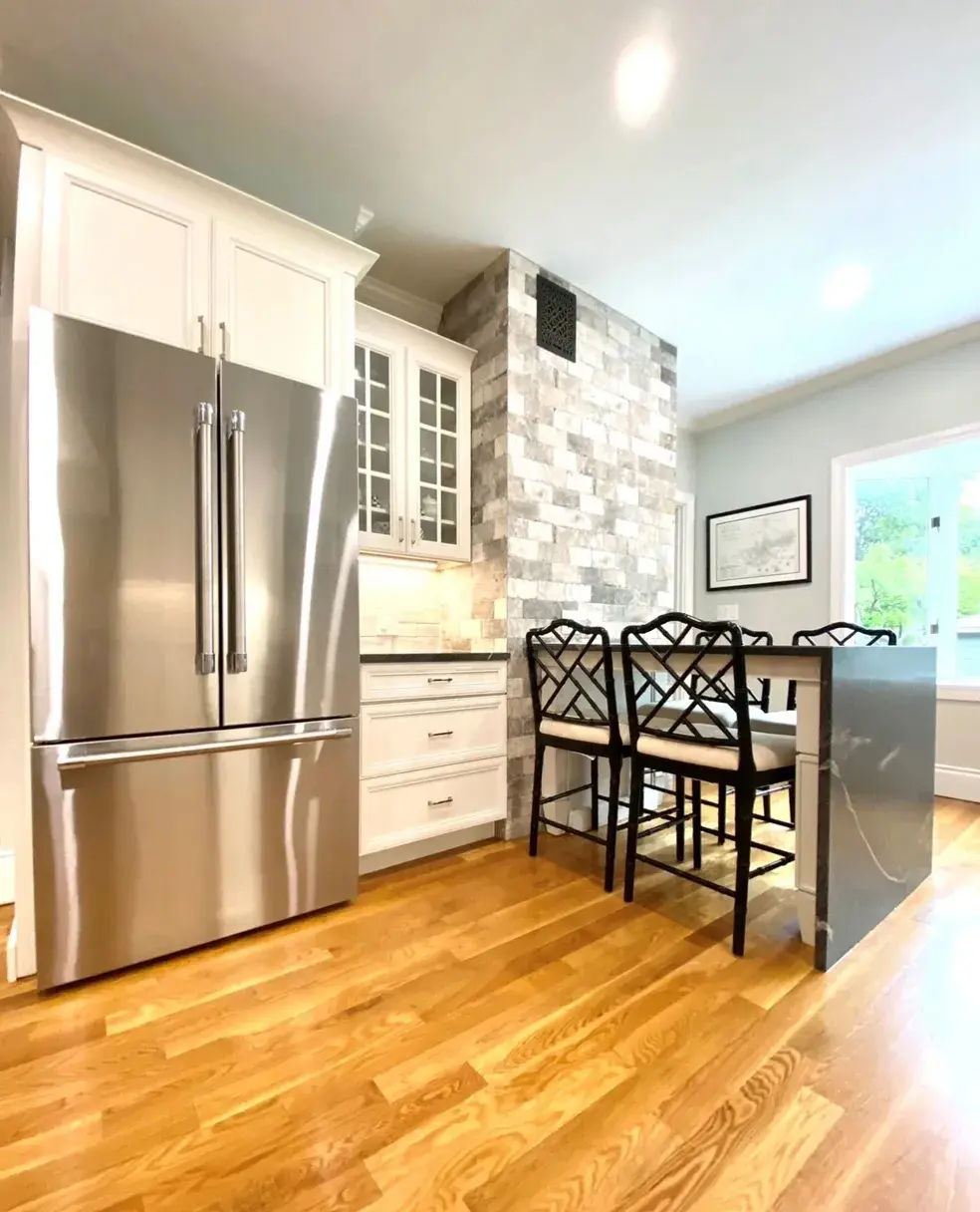 A kitchen with stainless steel appliances and wooden floors.