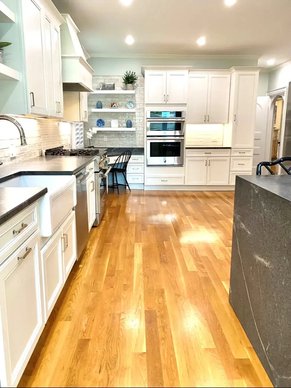 A kitchen with white cabinets and wood floors.