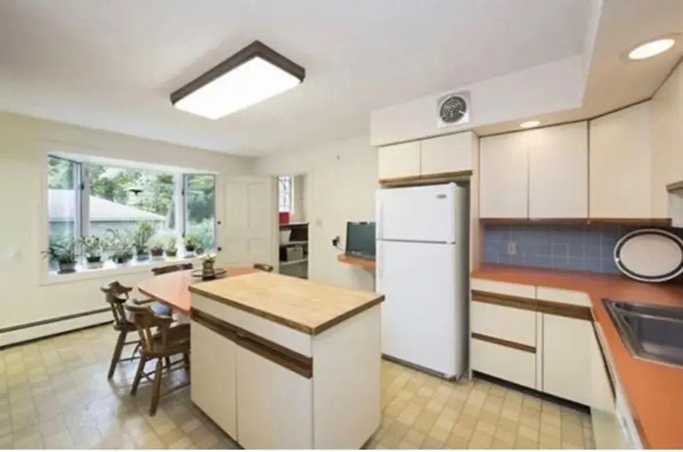 A kitchen with white cabinets and wooden floors.