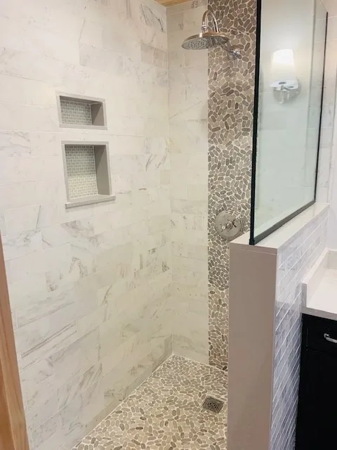 A bathroom with marble walls and floor, and a mirror.