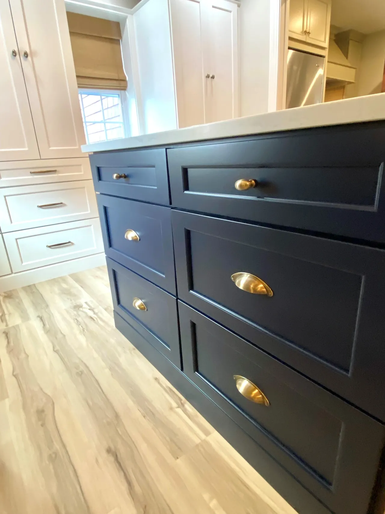 A kitchen with black cabinets and gold pulls.