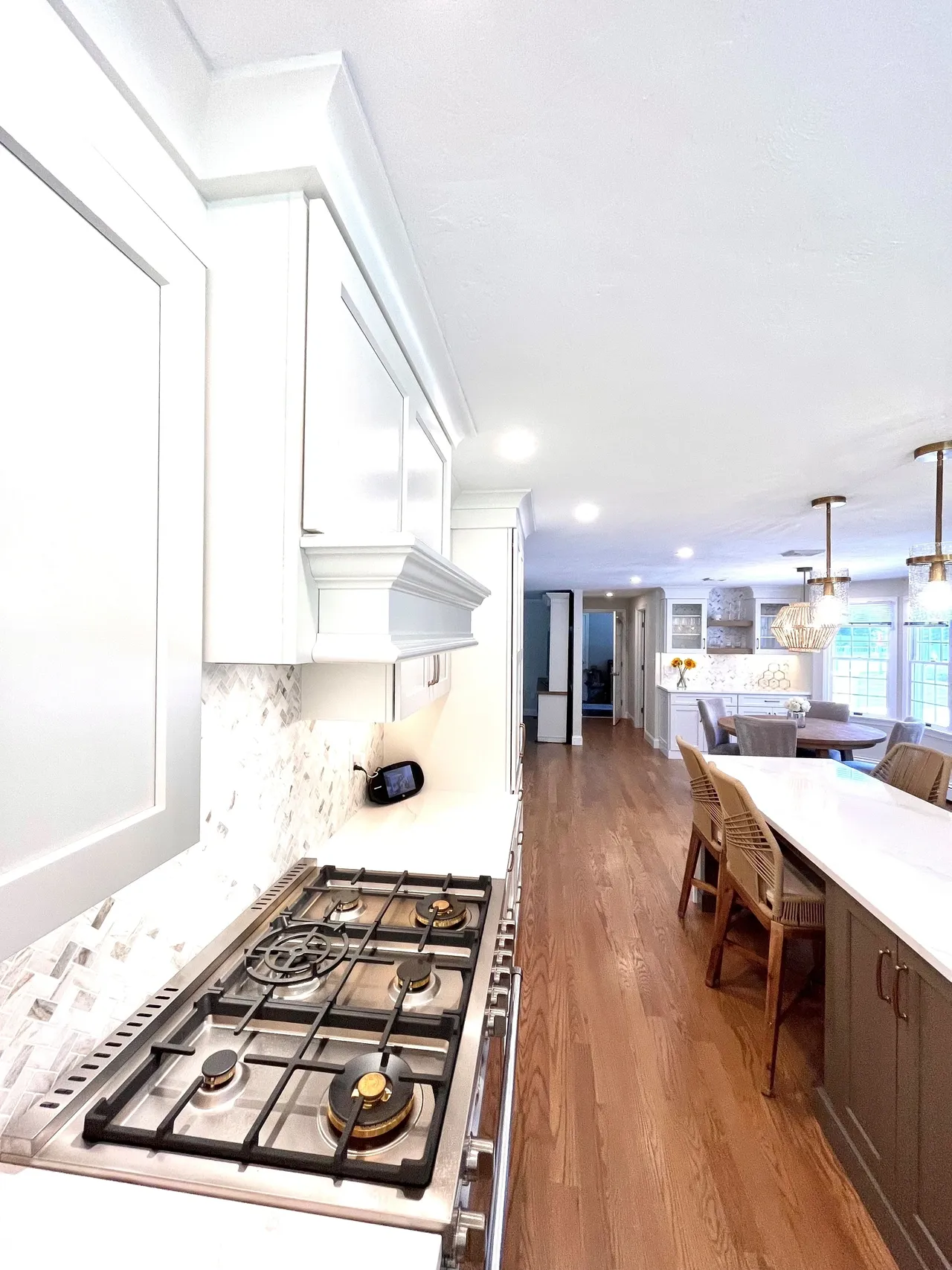 A kitchen with white cabinets and wood floors.