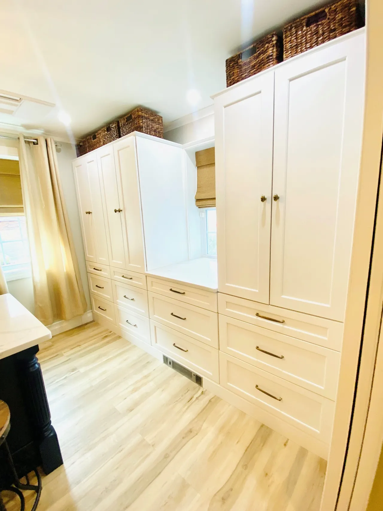 A kitchen with white cabinets and wood floors.