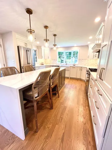 A kitchen with white cabinets and wood floors.