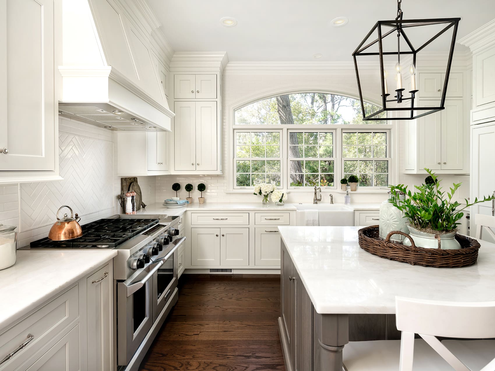 A kitchen with white cabinets and wooden floors.