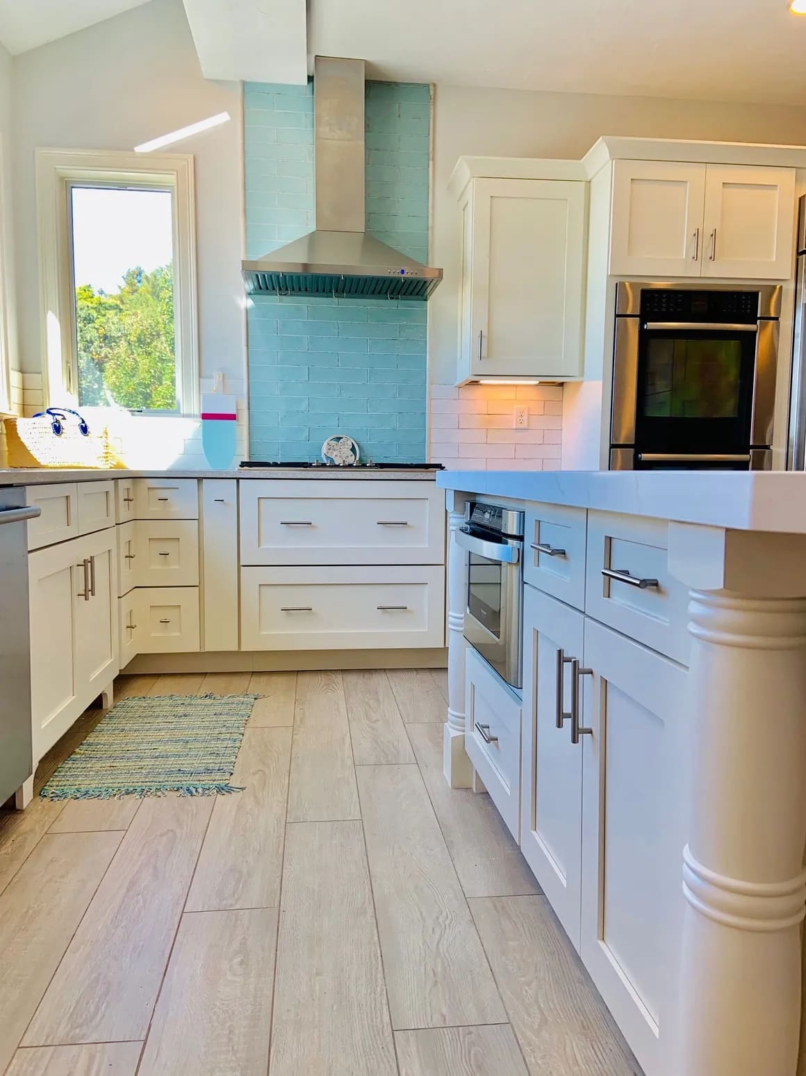 A kitchen with white cabinets and wood floors.