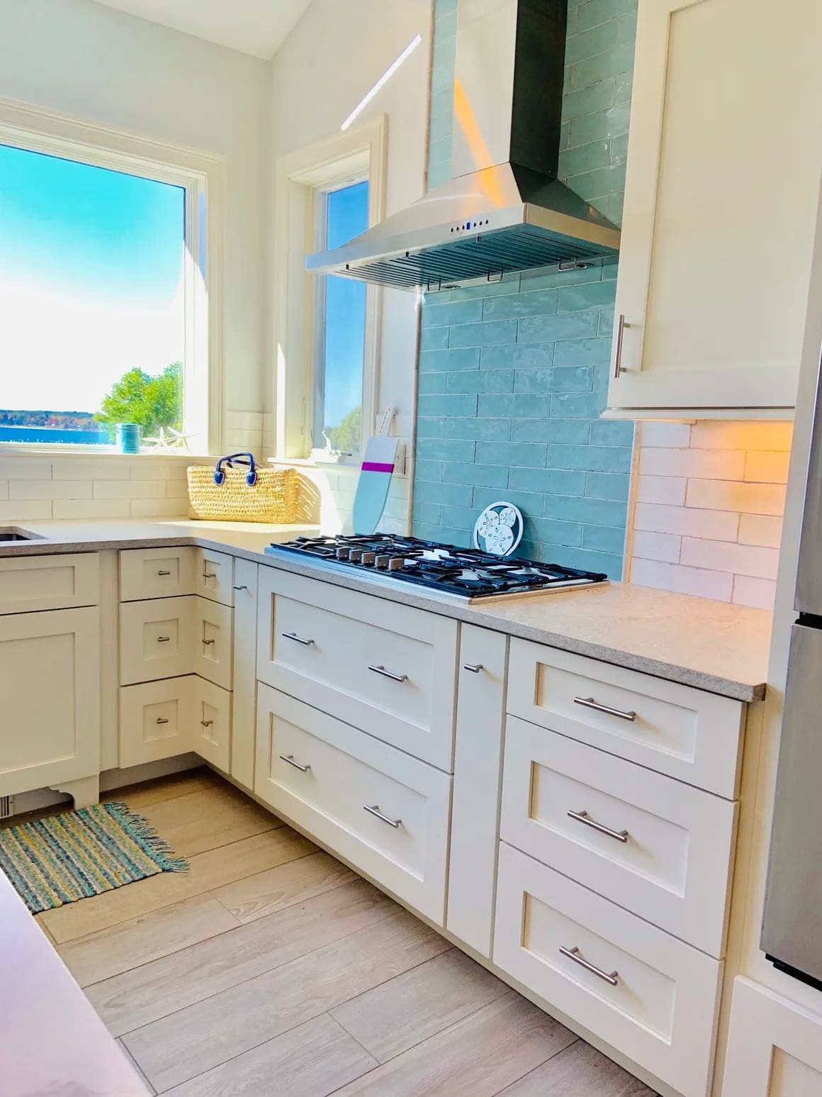 A kitchen with white cabinets and blue tile.