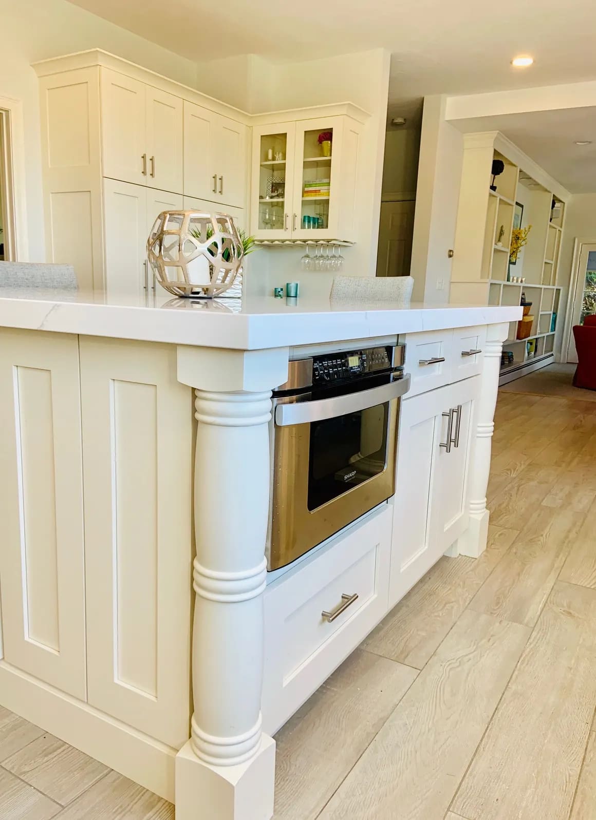 A kitchen with white cabinets and wood floors.