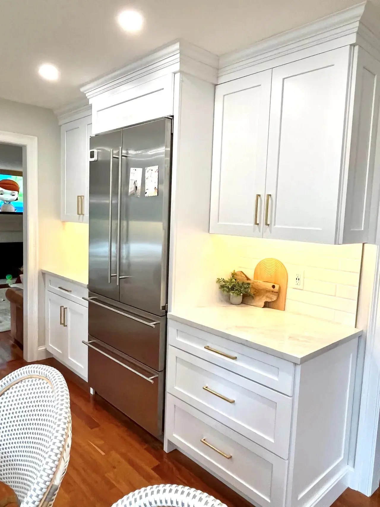 A kitchen with white cabinets and stainless steel refrigerator.