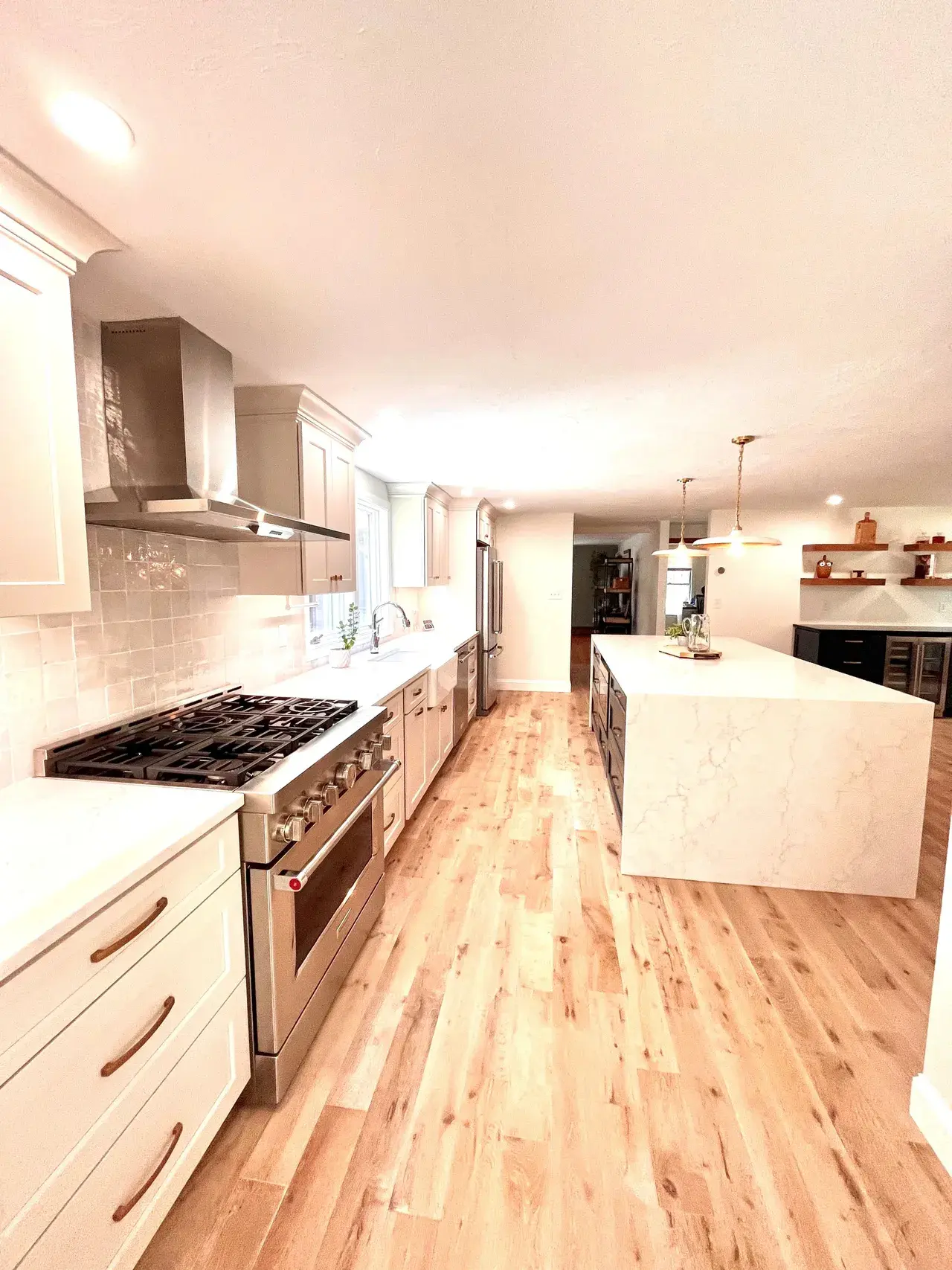 A kitchen with white cabinets and wood floors.