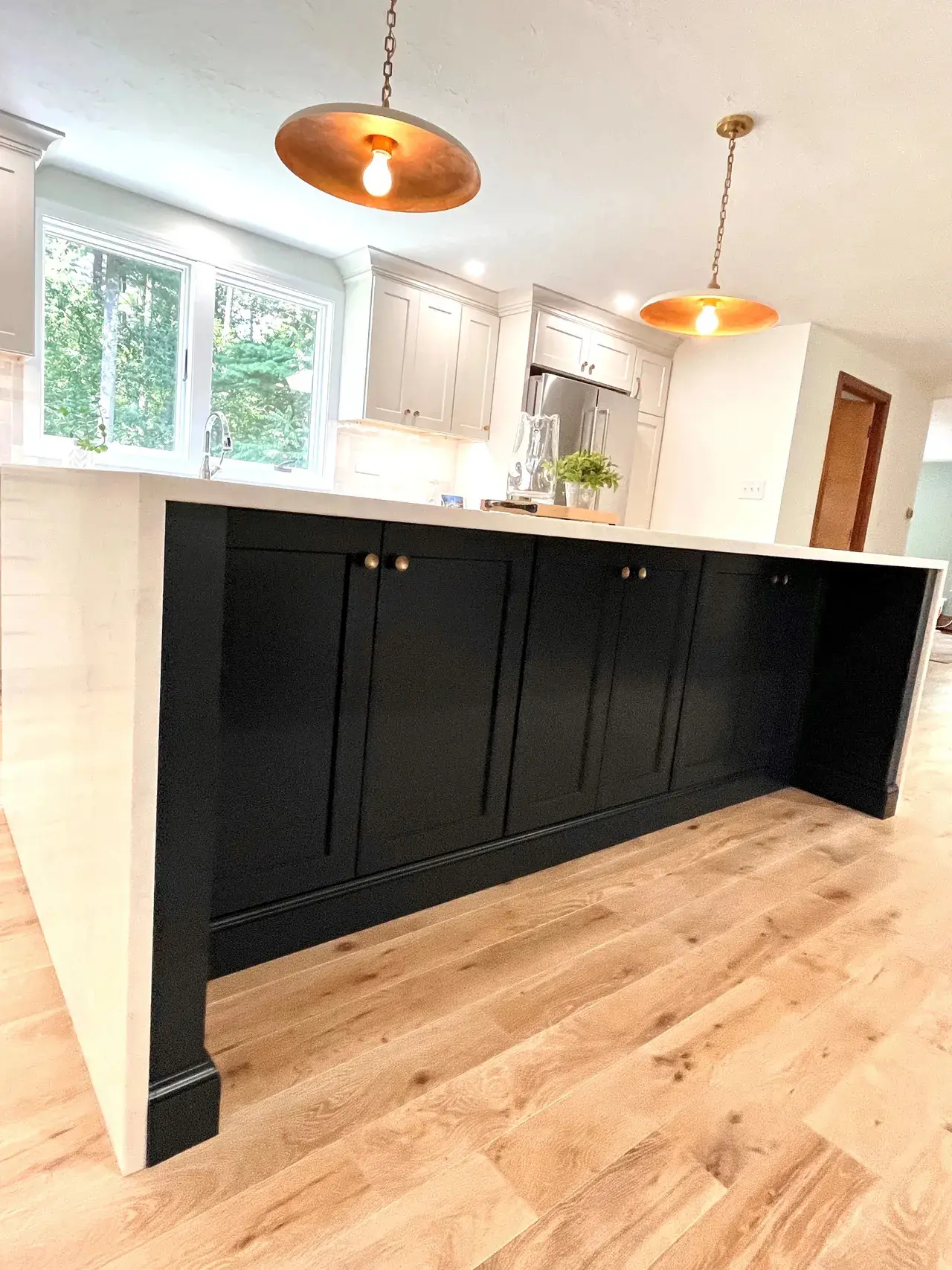 A kitchen with black cabinets and white counter tops.