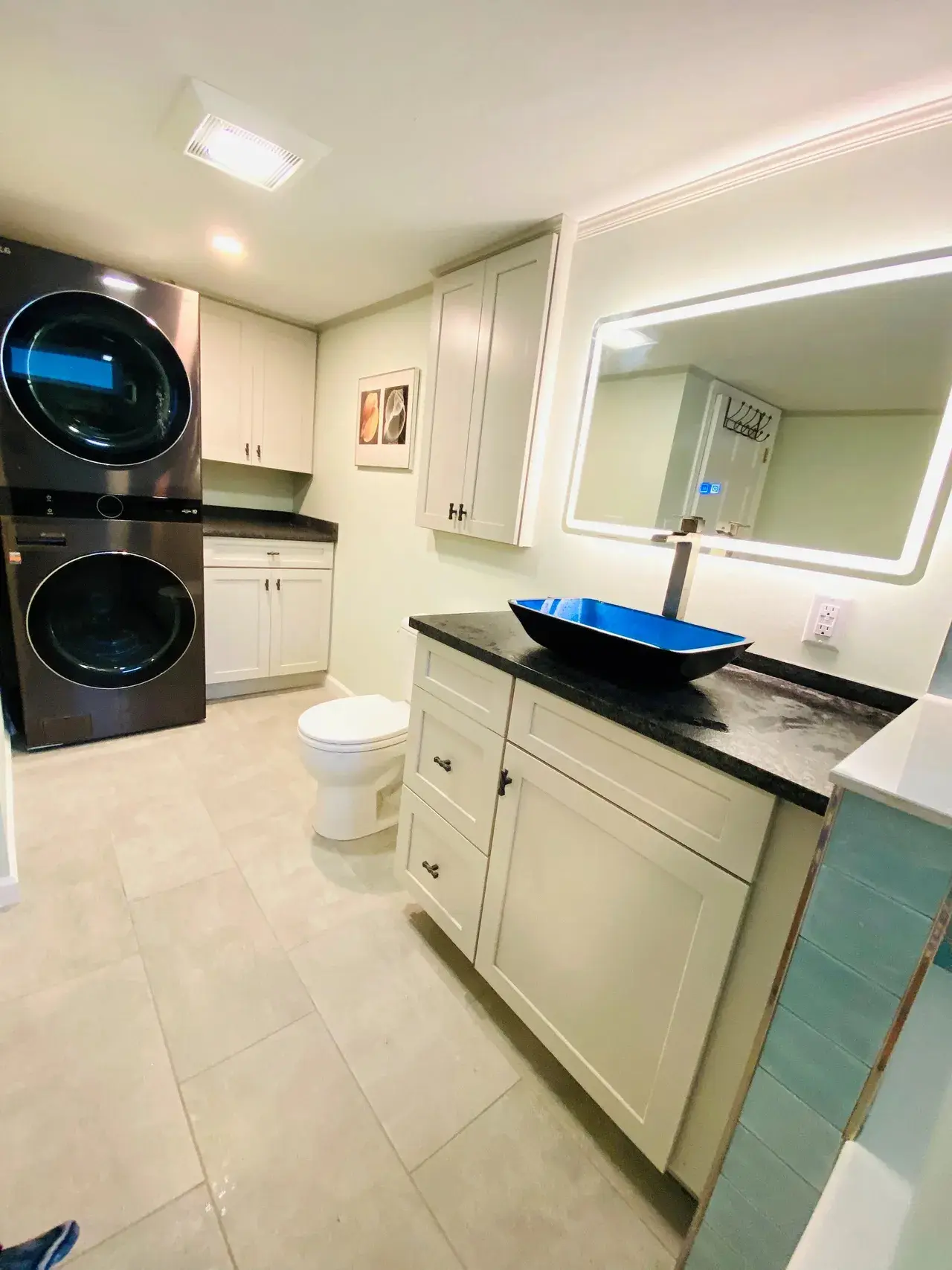 A bathroom with a sink, toilet and washer.