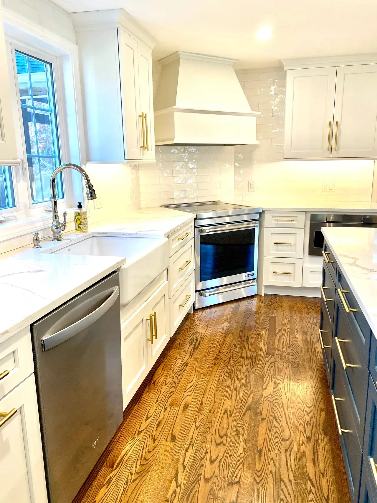 A kitchen with white cabinets and wood floors.