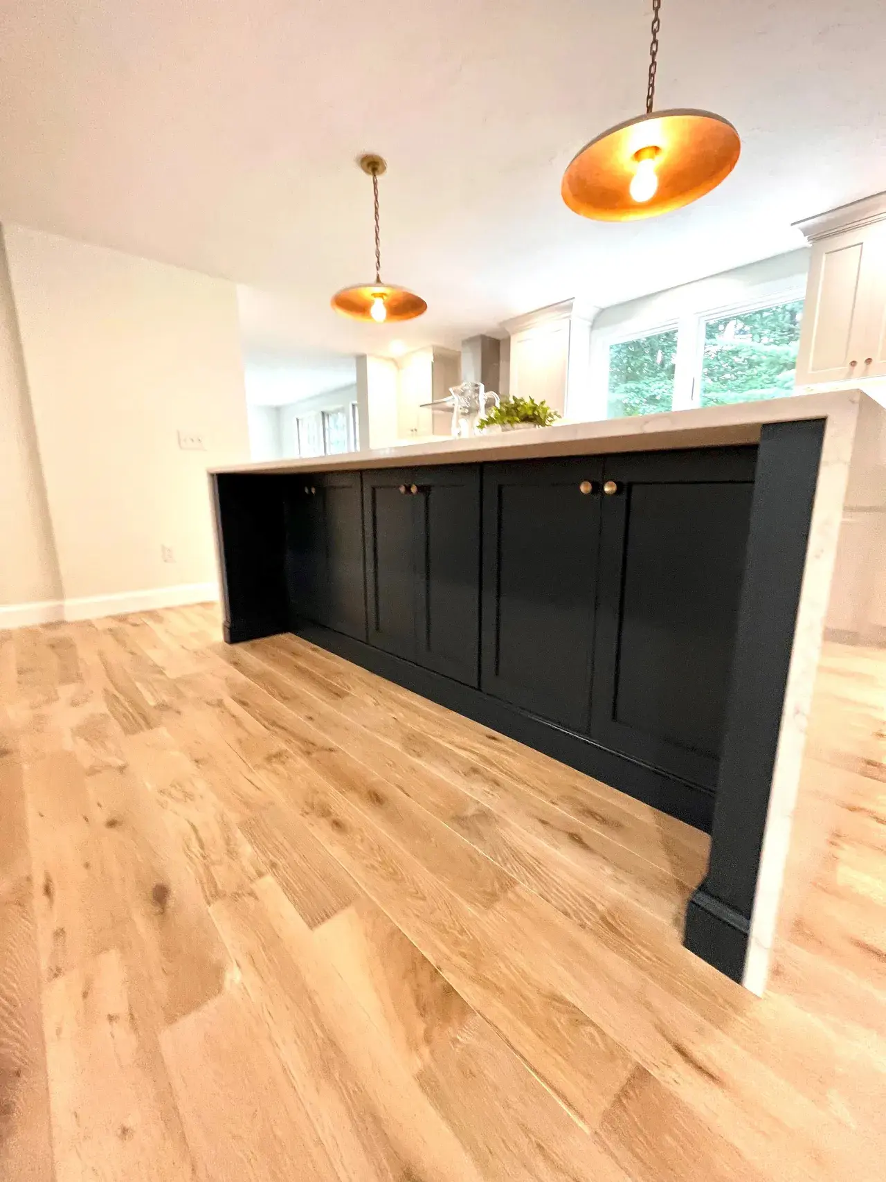 A kitchen with black cabinets and wood floors.