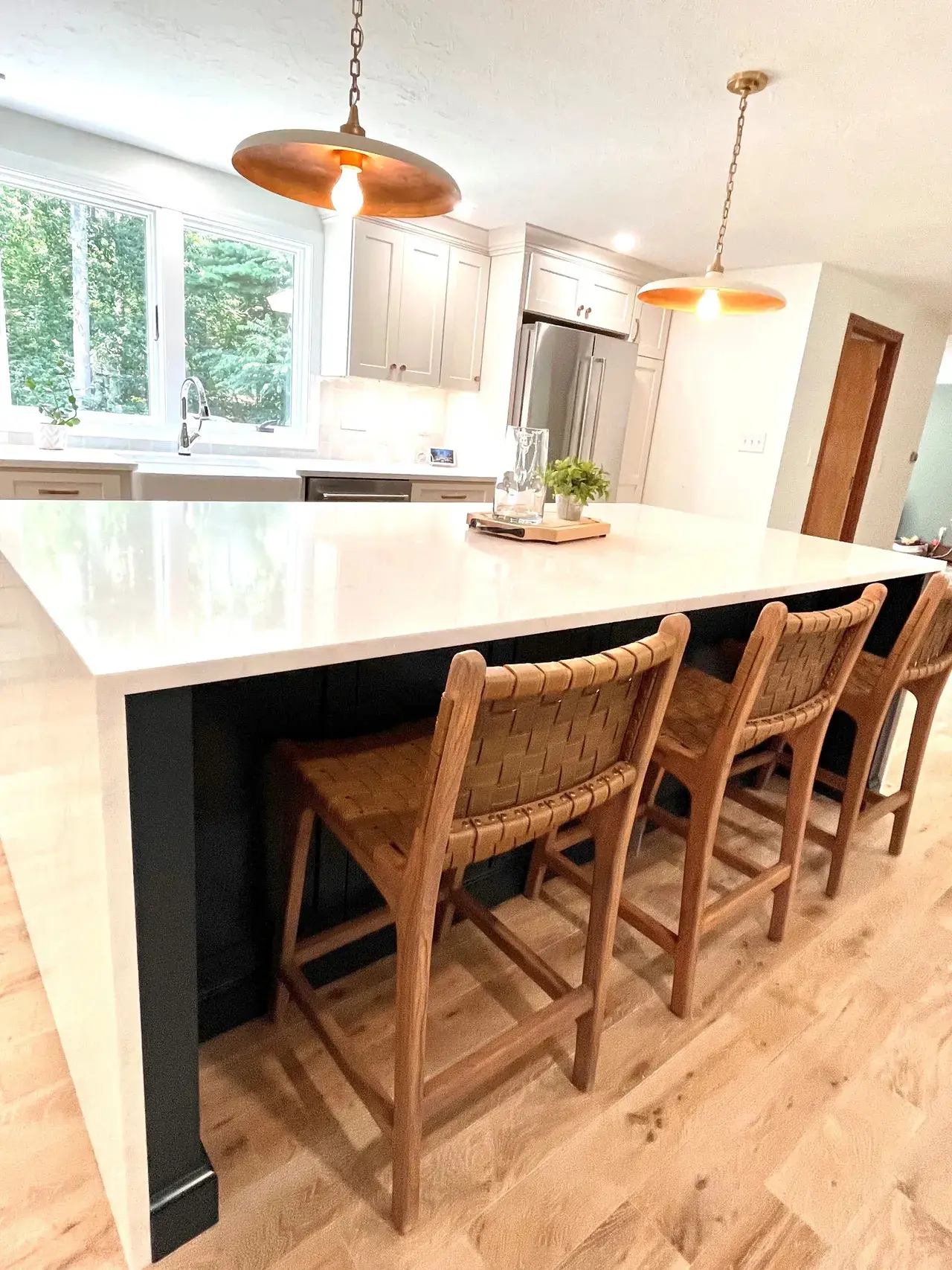 A kitchen with a large island and wooden chairs.