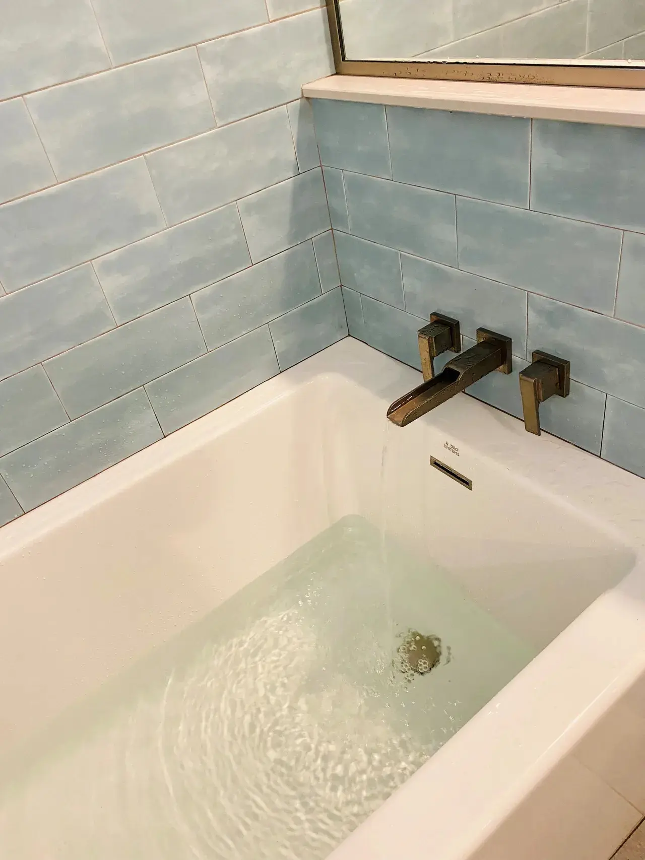 A bathtub with a faucet and tile wall.