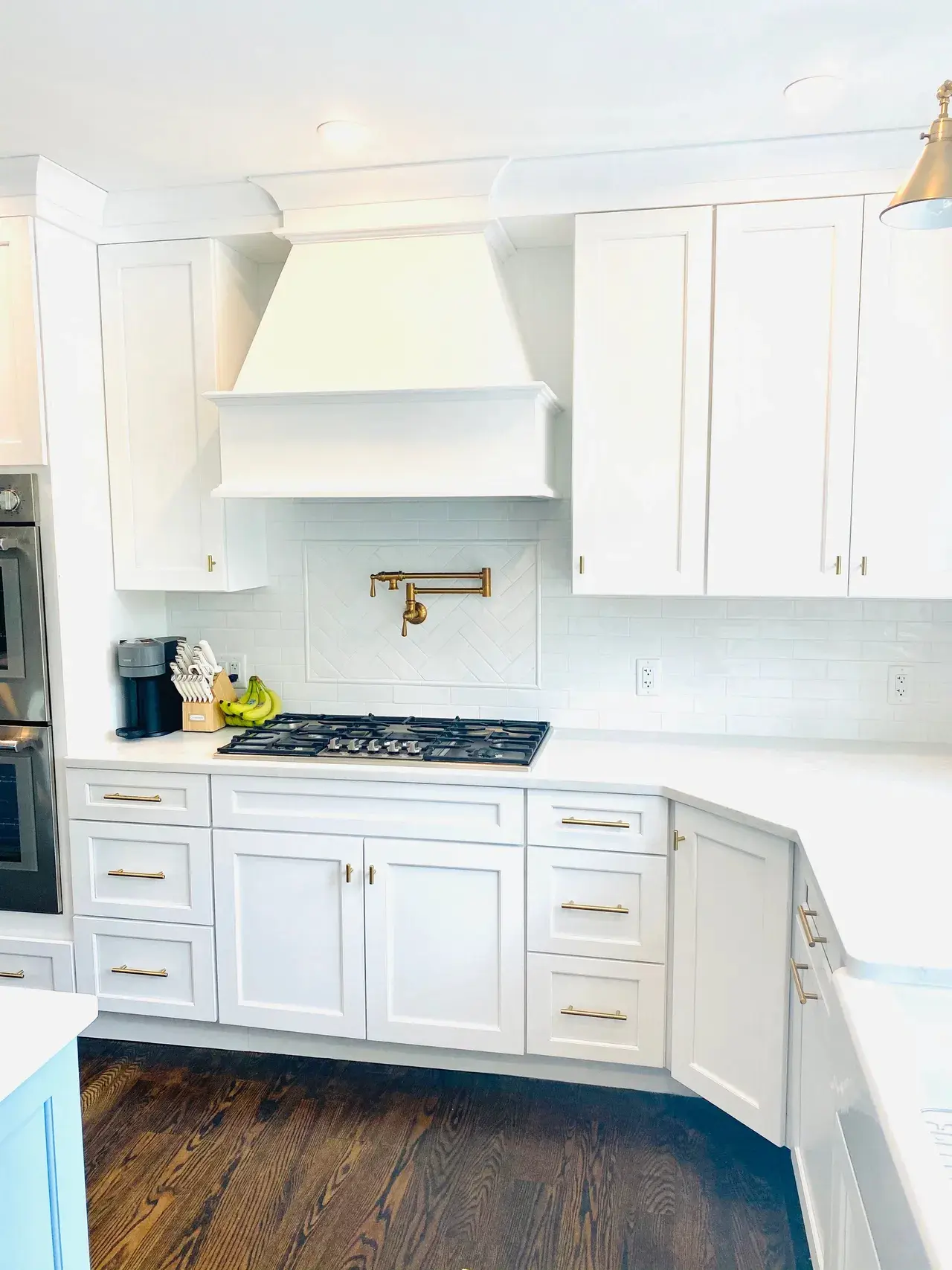 A kitchen with white cabinets and wood floors.