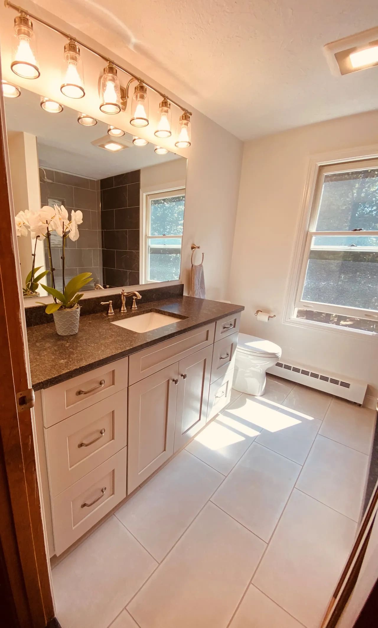 A bathroom with white cabinets and black counter tops.