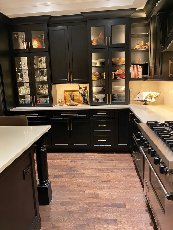 A kitchen with dark cabinets and wood floors.