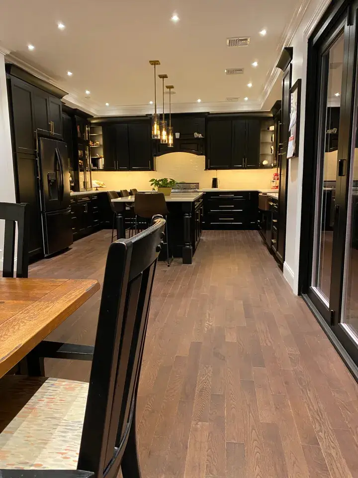 A kitchen with black cabinets and wooden floors