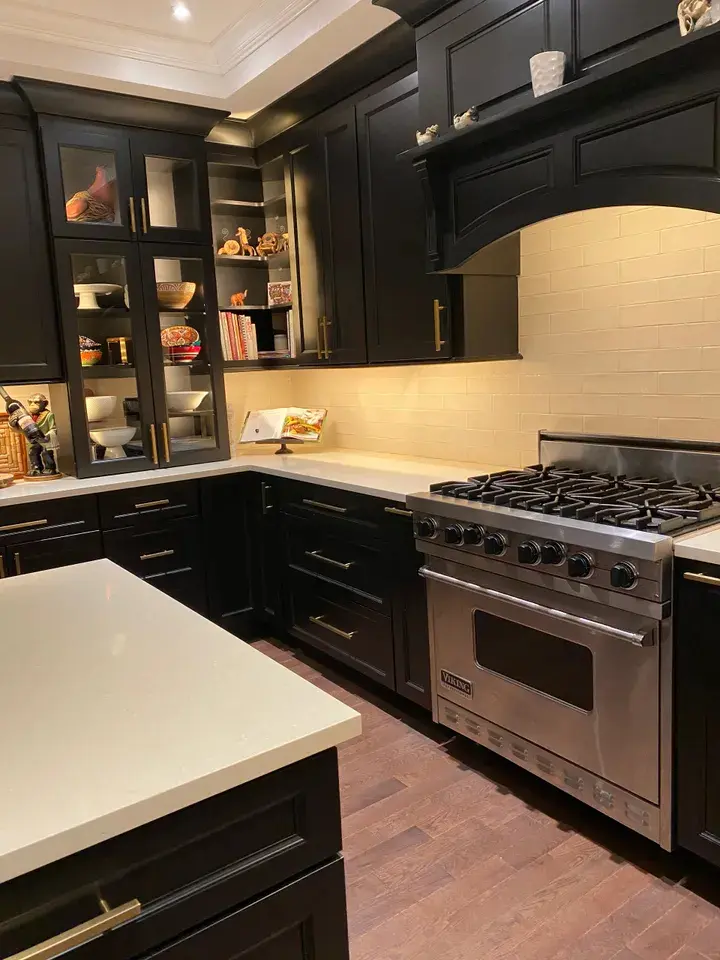 A kitchen with black cabinets and white counters.