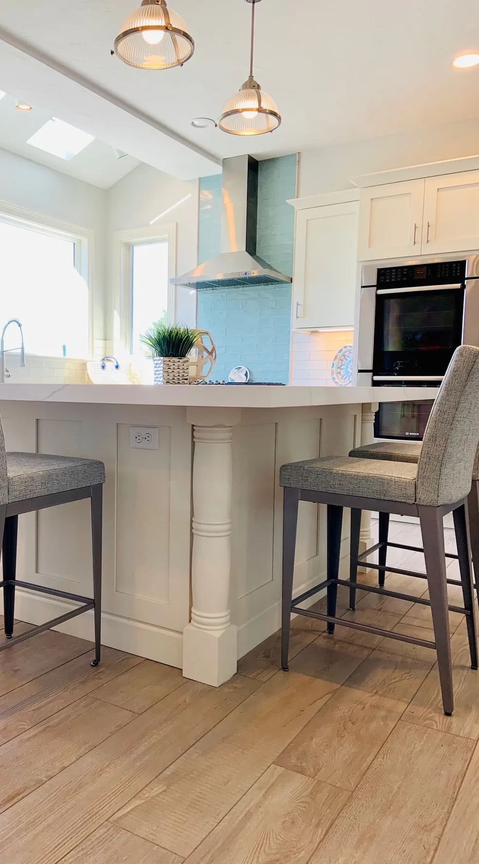 A kitchen with white cabinets and gray chairs.