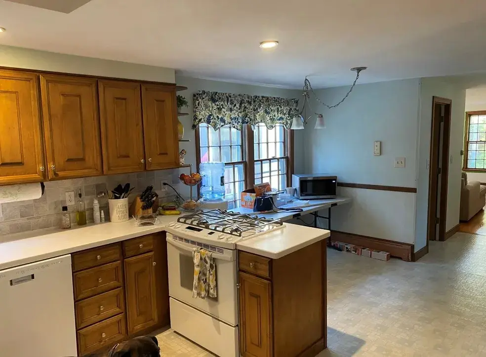 A kitchen with wooden cabinets and white counters.