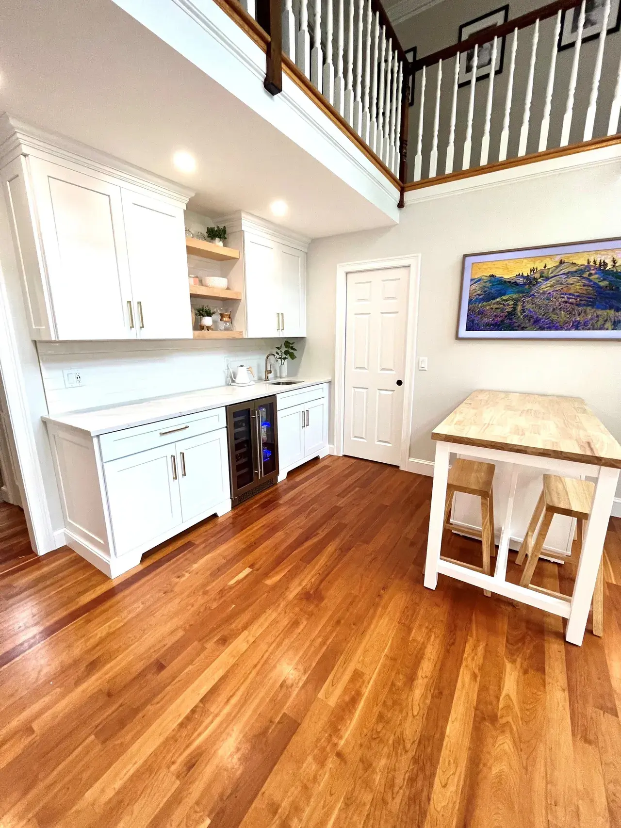 A kitchen with wooden floors and white cabinets.