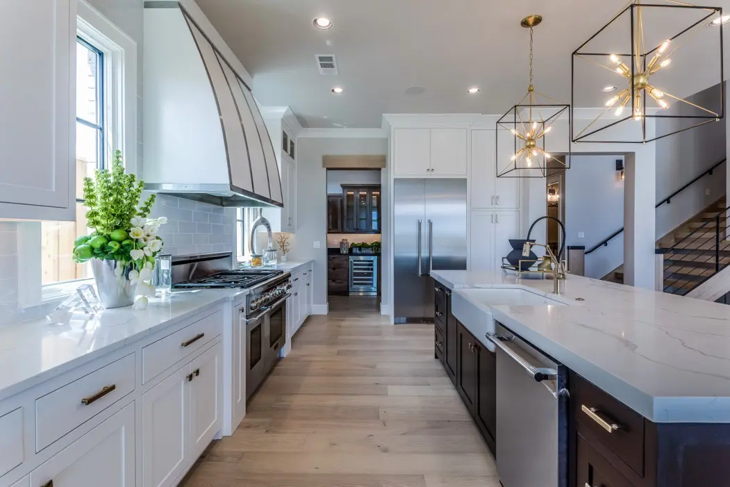 A kitchen with white cabinets and wood floors.